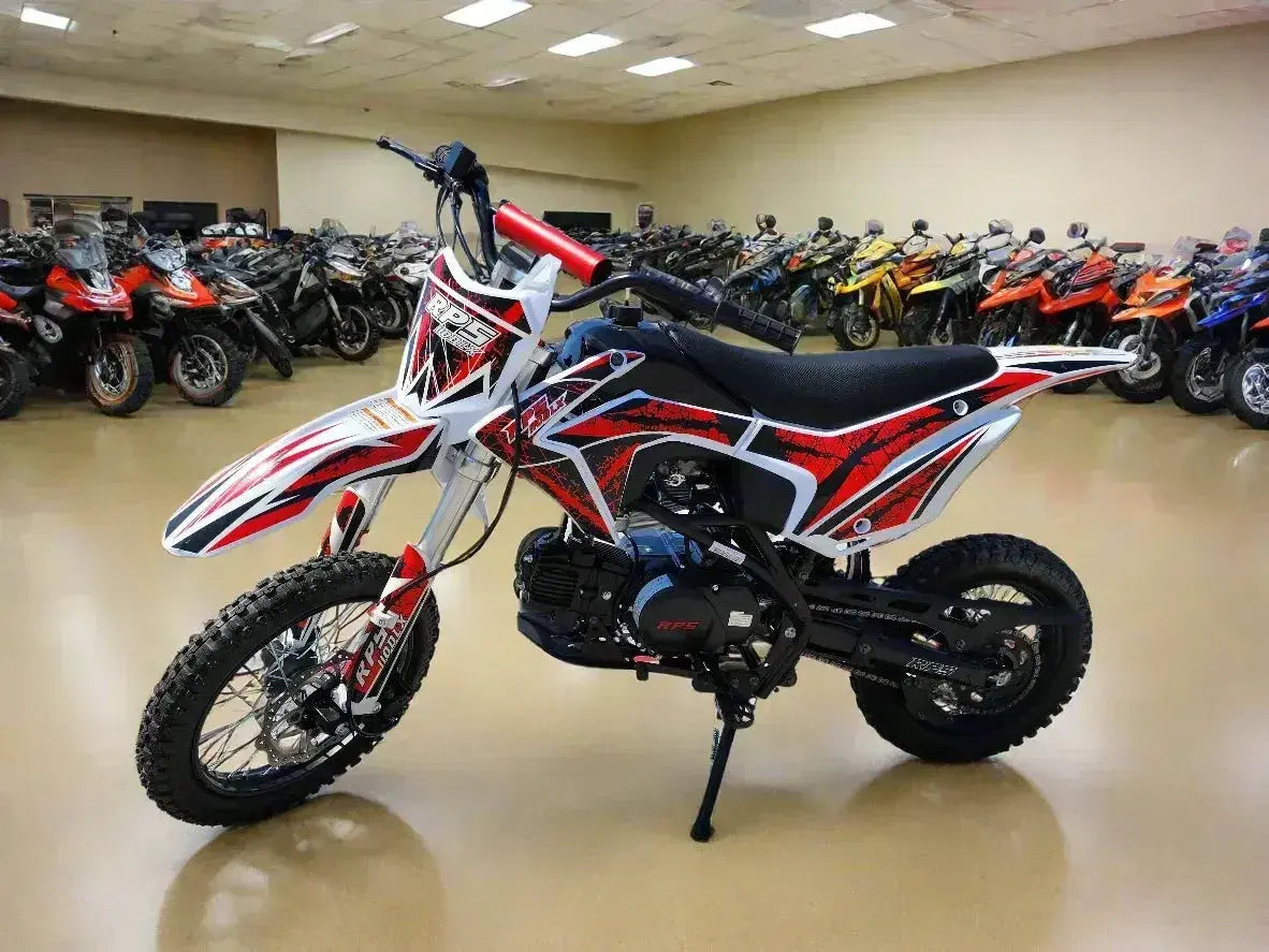 Red and white 110cc dirt bike with knobby tires displayed in a showroom with other motorcycles