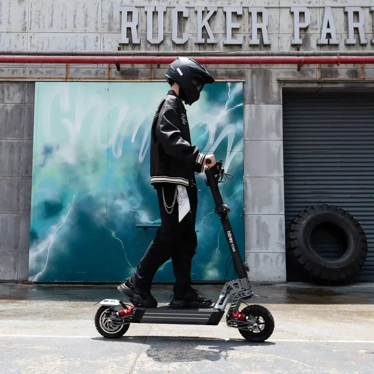 Person wearing helmet riding electric scooter outdoors near urban wall