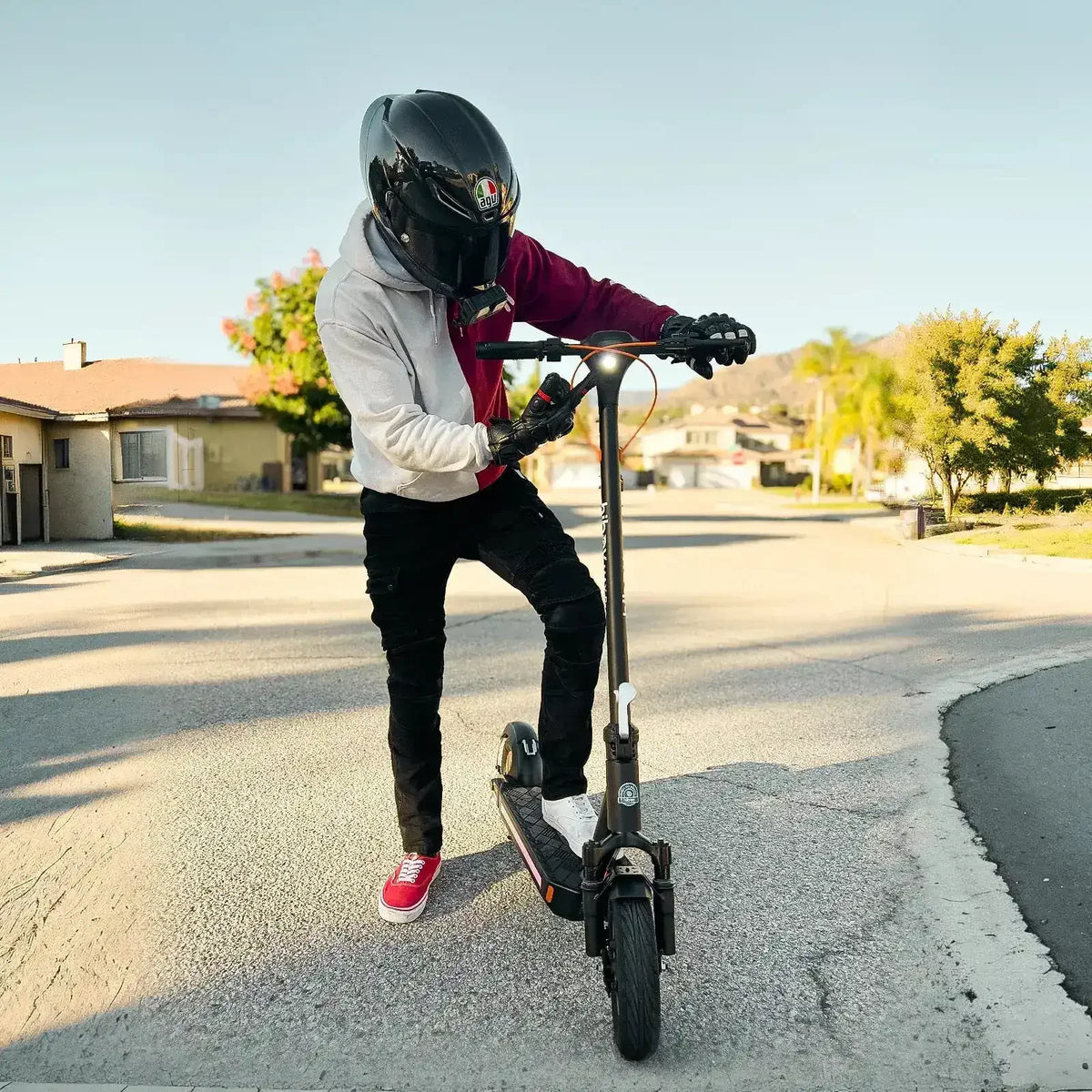 Person wearing helmet riding an electric scooter on a suburban street