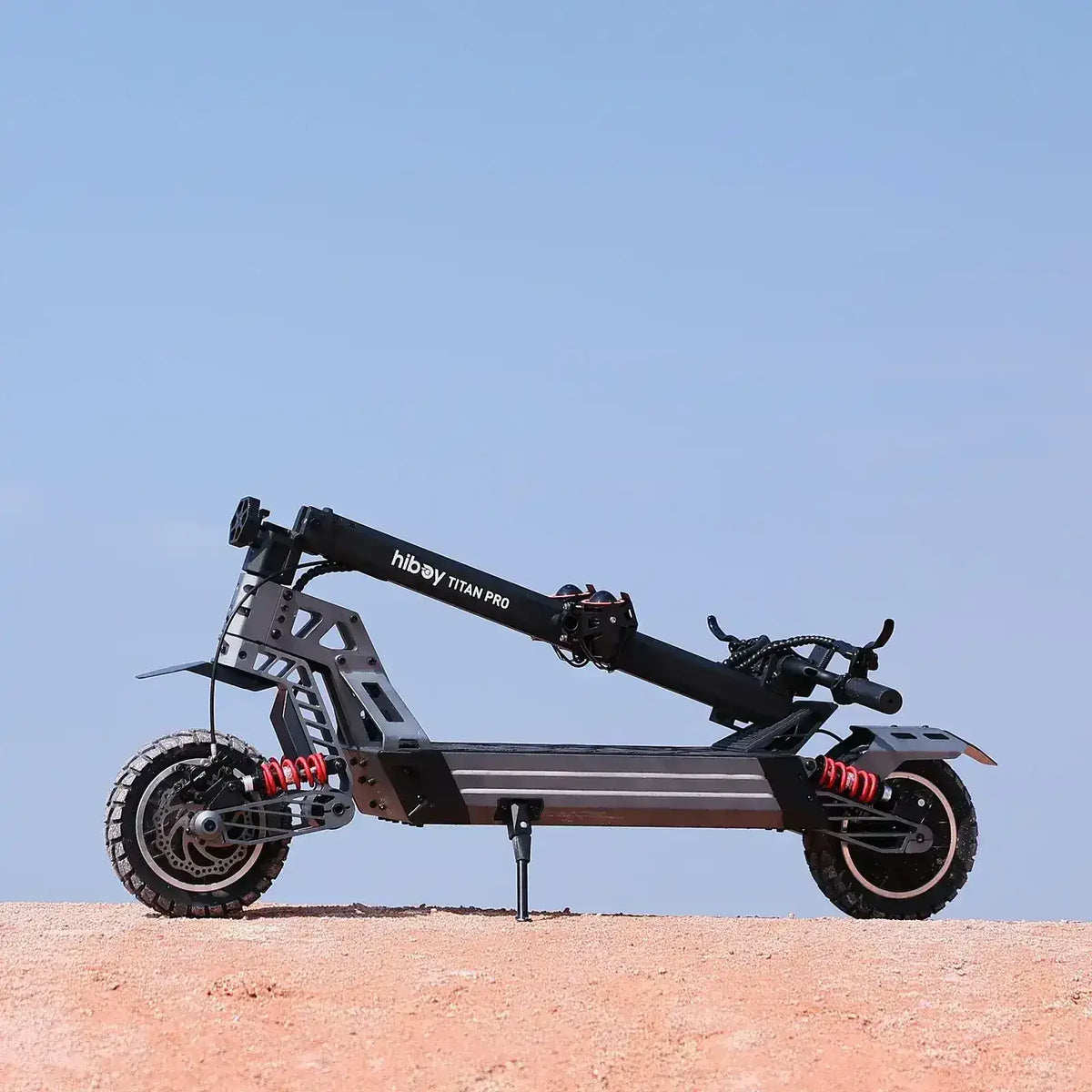 Folded Hiboy Titan Pro electric scooter with off-road tires and suspension on dirt terrain