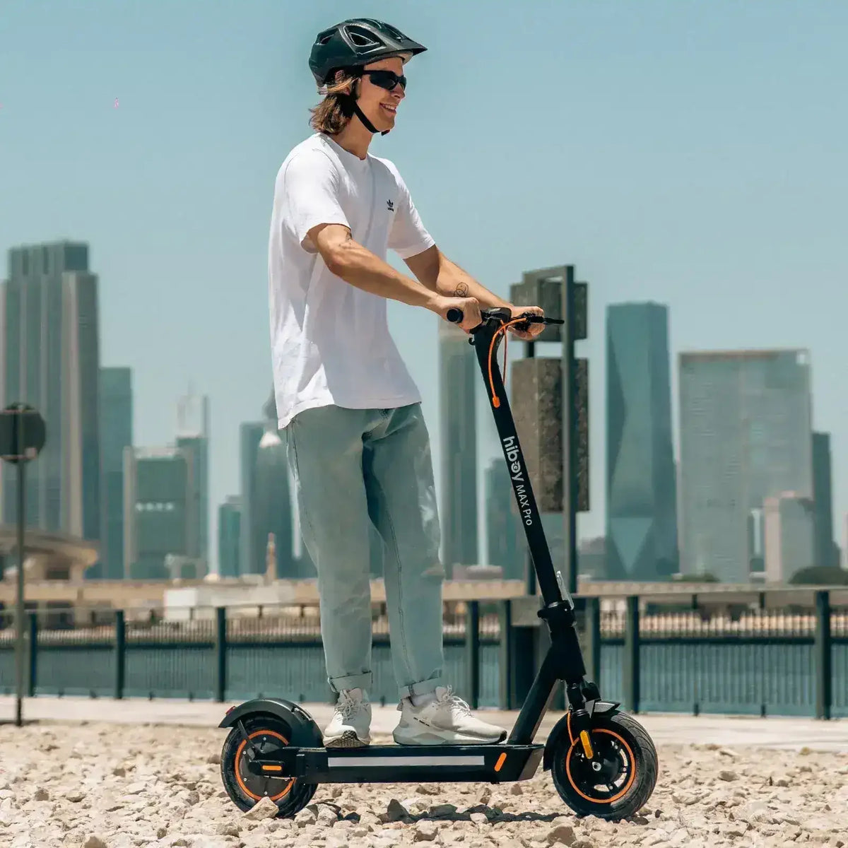 Man riding electric scooter outdoors with city skyline in the background