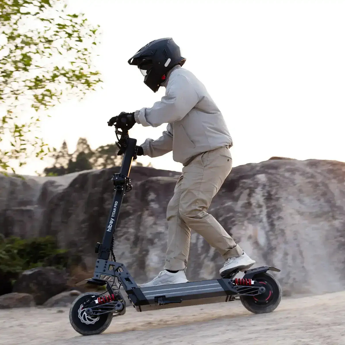 Person riding off-road electric scooter with helmet on dirt trail outdoors