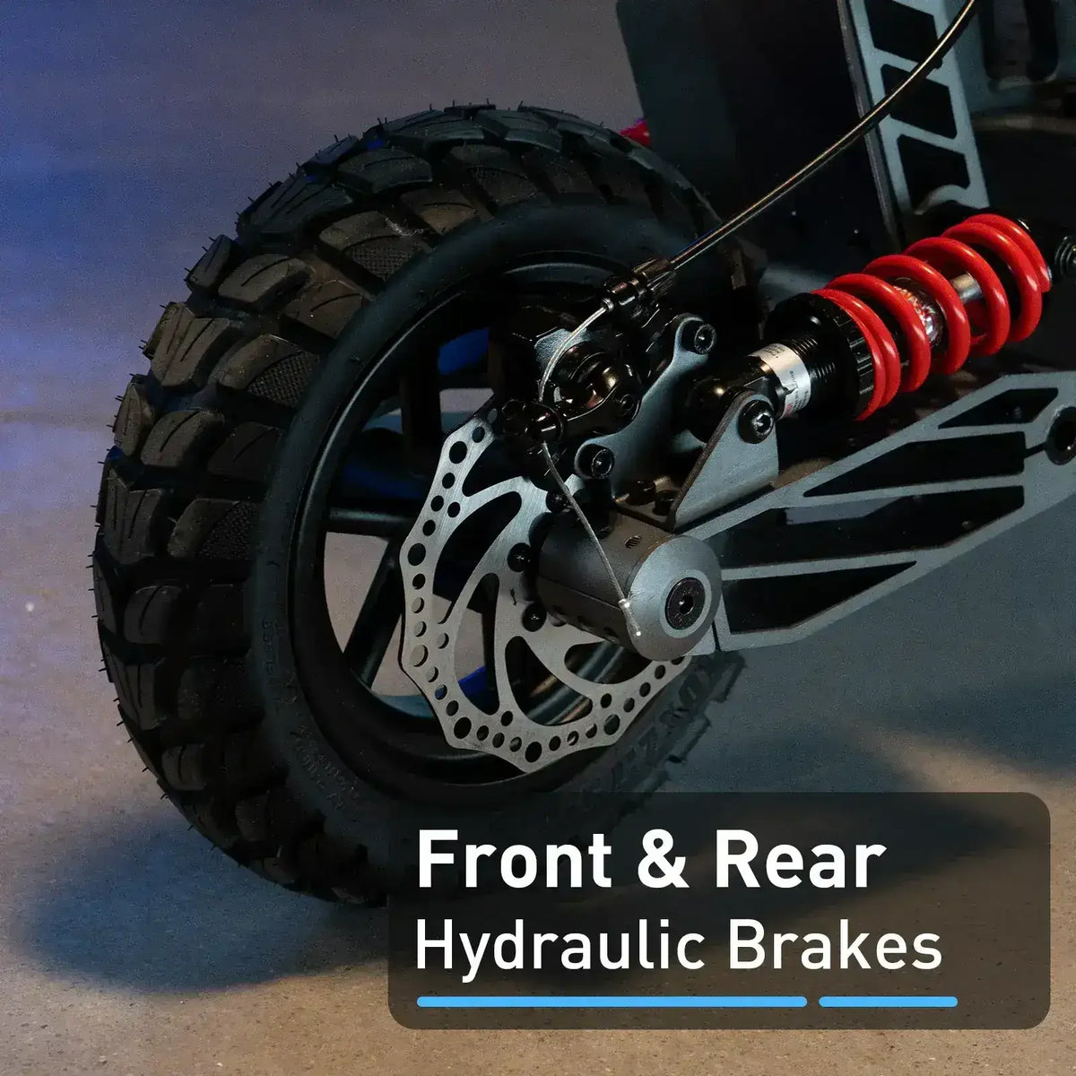 Close-up of rugged ATV or dirt bike wheel with hydraulic disc brake and red suspension spring.