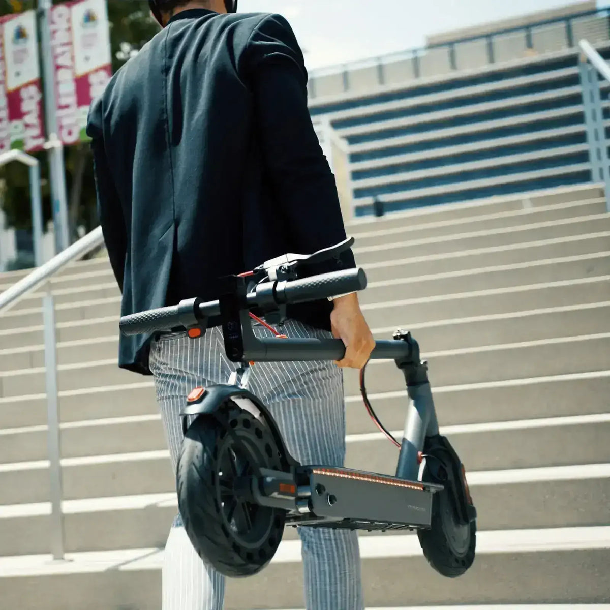 Person carrying a folded electric scooter up outdoor stairs for urban commuting