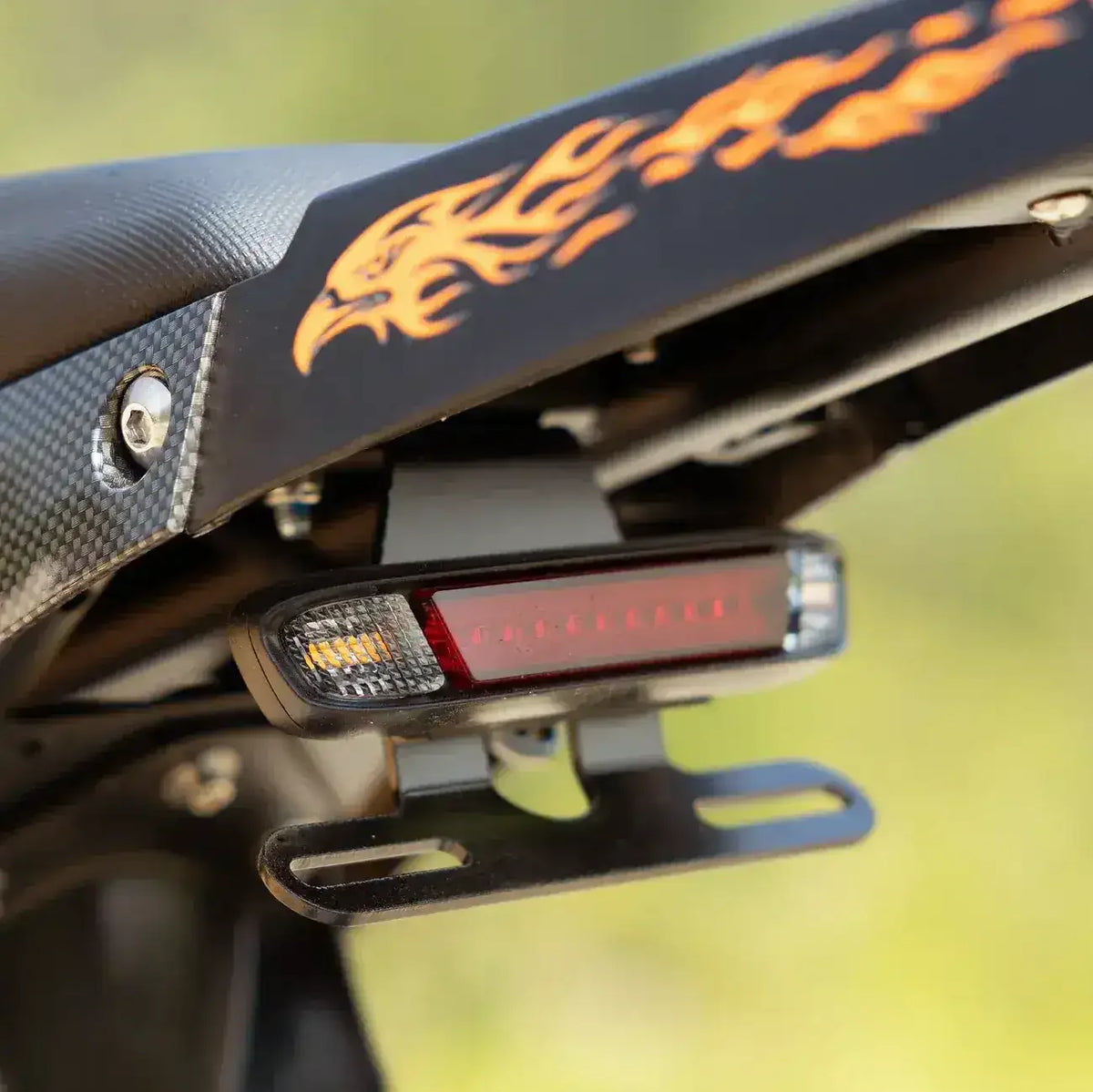 Close-up of ATV rear fender with flame decal and LED tail light, license plate bracket visible.