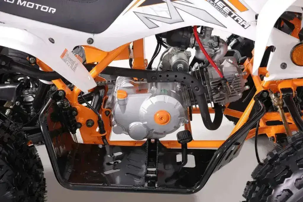 Close-up of ATV engine and frame with orange and white body, off-road tires visible