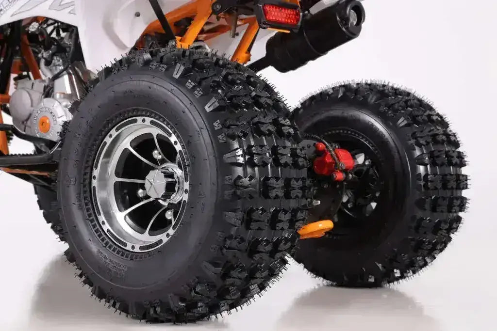 Close-up of rear ATV knobby tires and suspension on a white background