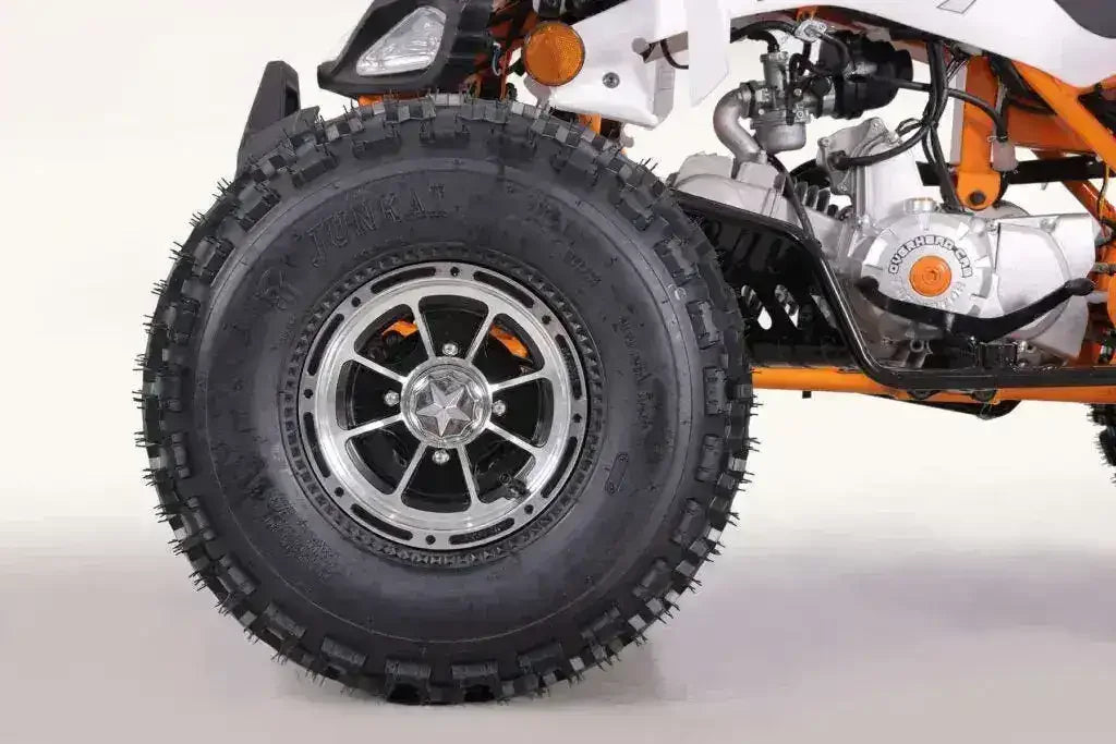 Close-up of an off-road ATV tire and engine on a white background