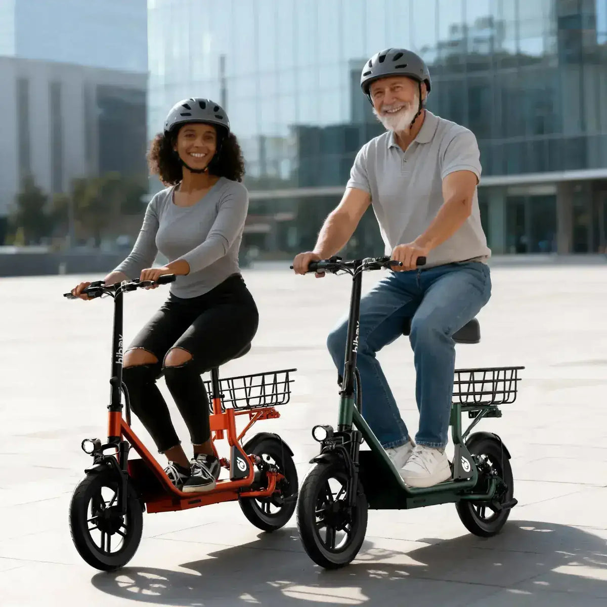 Two people riding electric scooters with baskets, wearing helmets in an urban plaza