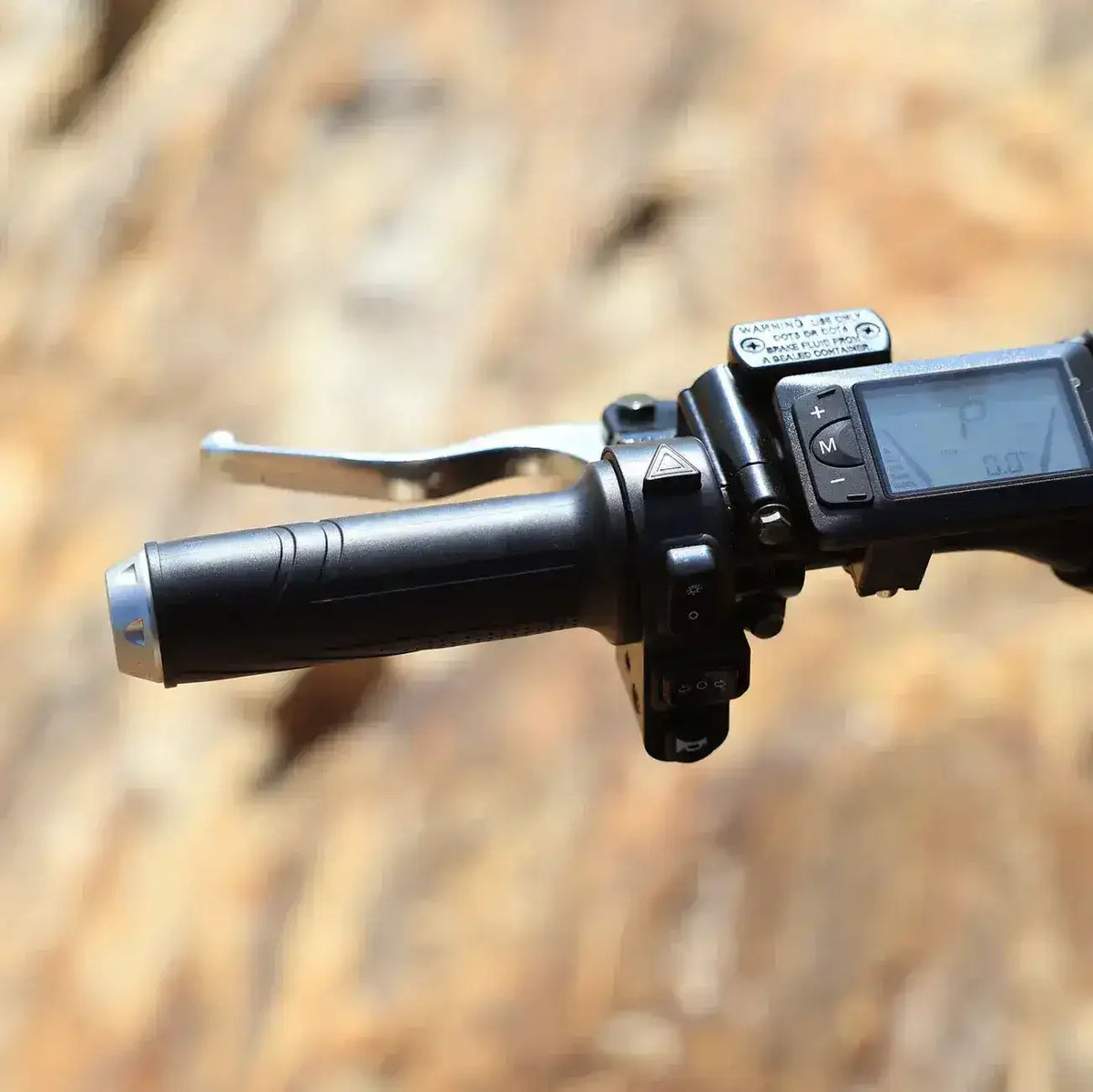 ATV or dirt bike handlebar with digital display and control buttons, outdoor setting