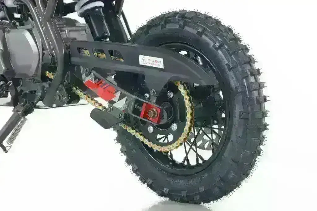 Close-up of dirt bike rear wheel, off-road tire, suspension, and drive chain