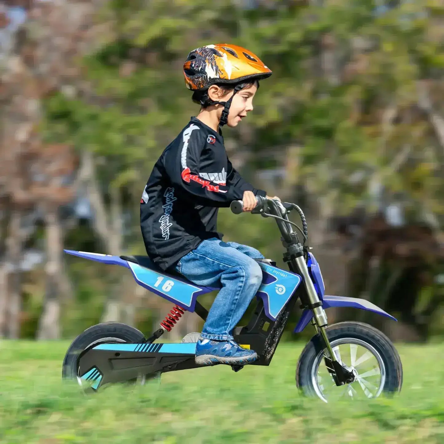 Child riding a blue electric dirt bike outdoors wearing a safety helmet