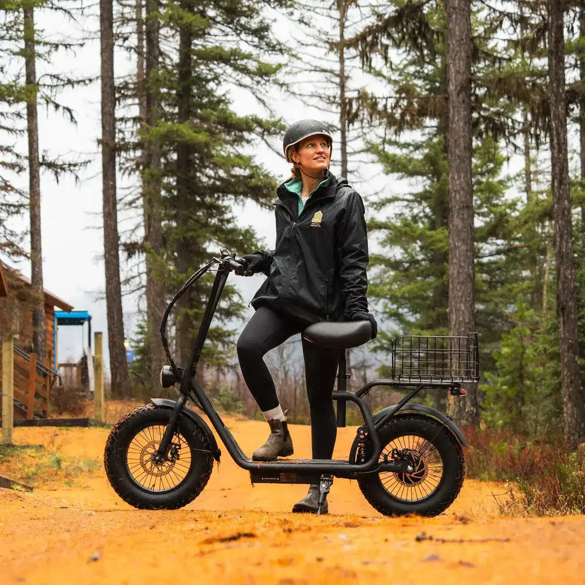 Woman in helmet standing with fat tire electric scooter on a forest trail