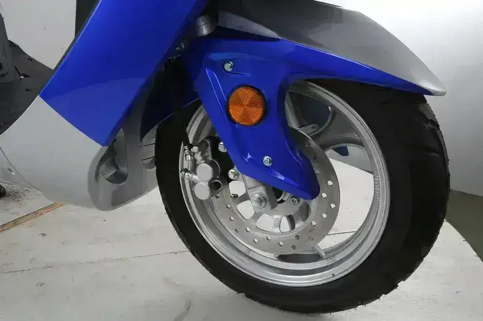 Close-up of the RPS Adventure scooter front wheel showing drilled disc brake, silver caliper and blue fender