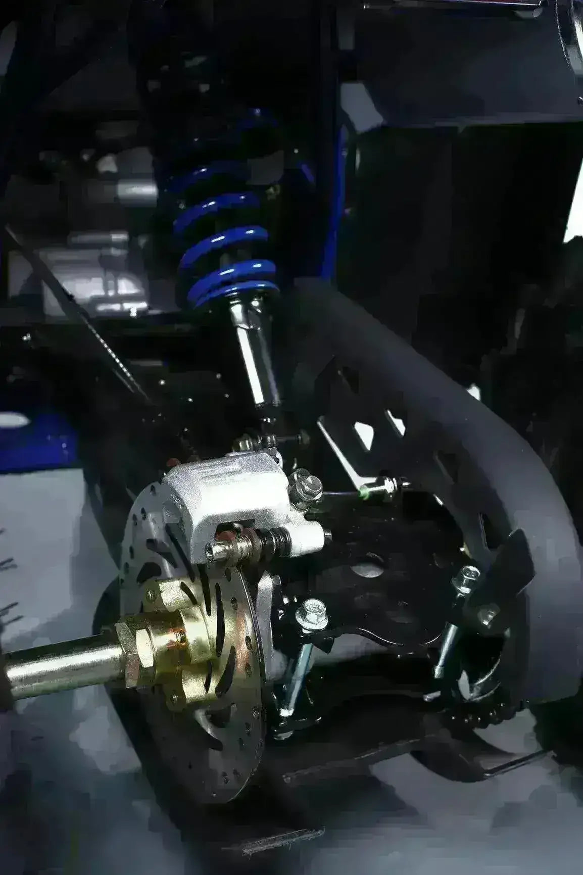 Close-up of ATV suspension system, disc brake, and coil spring on utility four wheeler