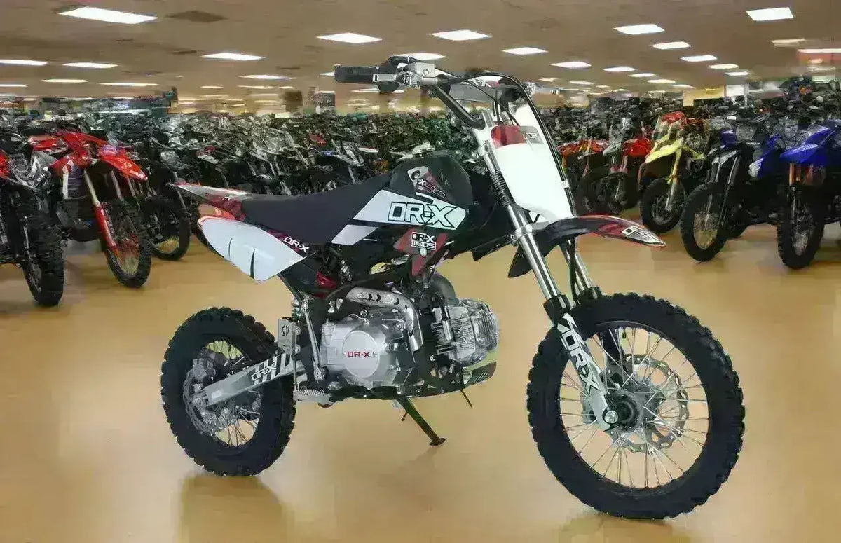 125cc youth dirt bike with knobby tires on showroom floor, surrounded by other dirt bikes