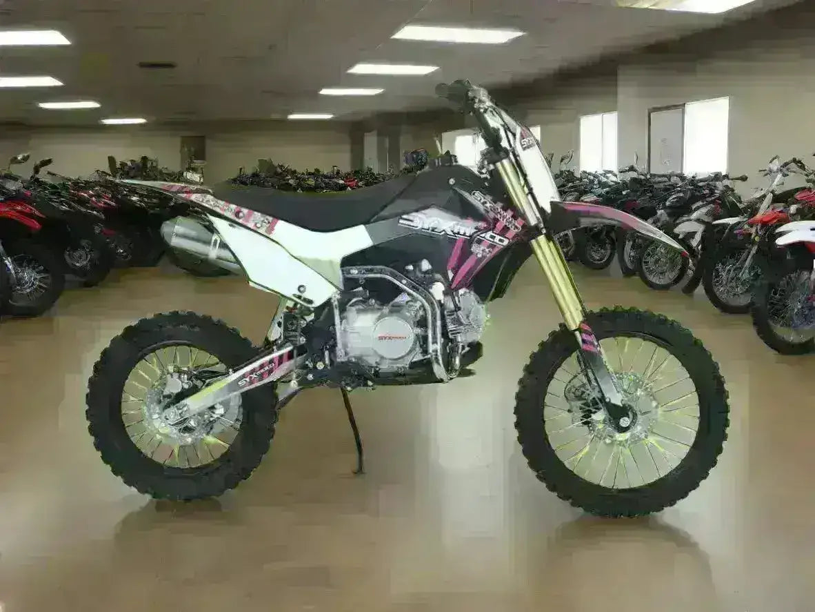 125cc youth dirt bike with off-road tires on showroom floor, surrounded by similar bikes