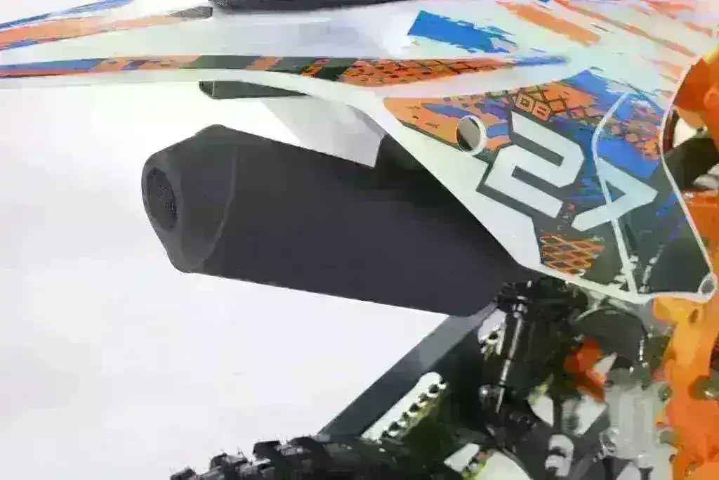 Close-up of a youth 125cc dirt bike exhaust and colorful graphic panel.