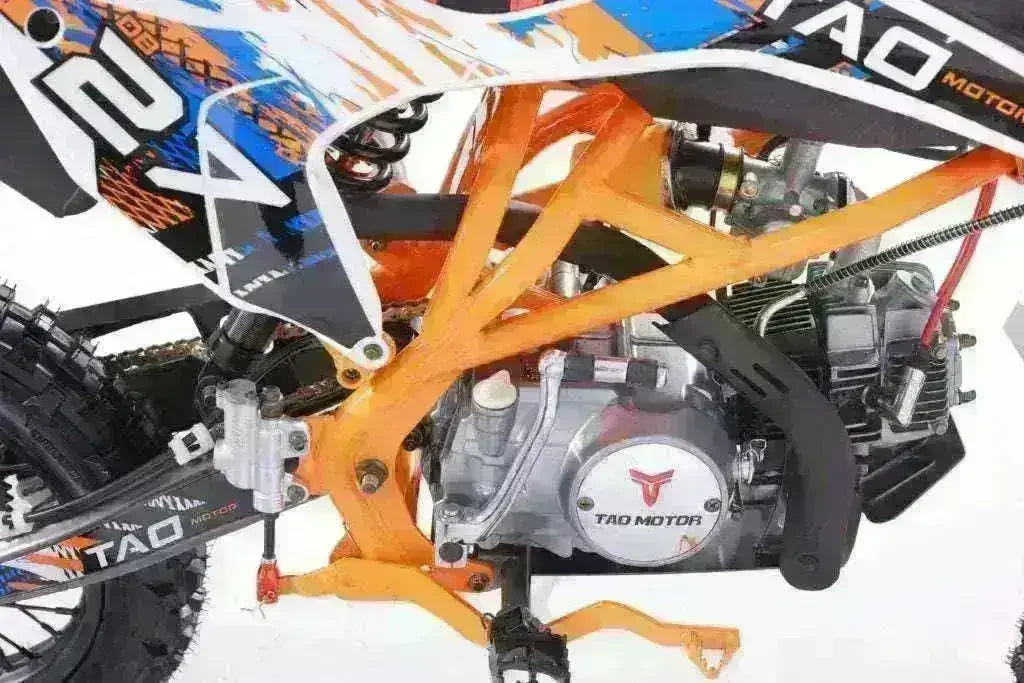 Close-up of 125cc youth dirt bike engine with orange frame and off-road tire