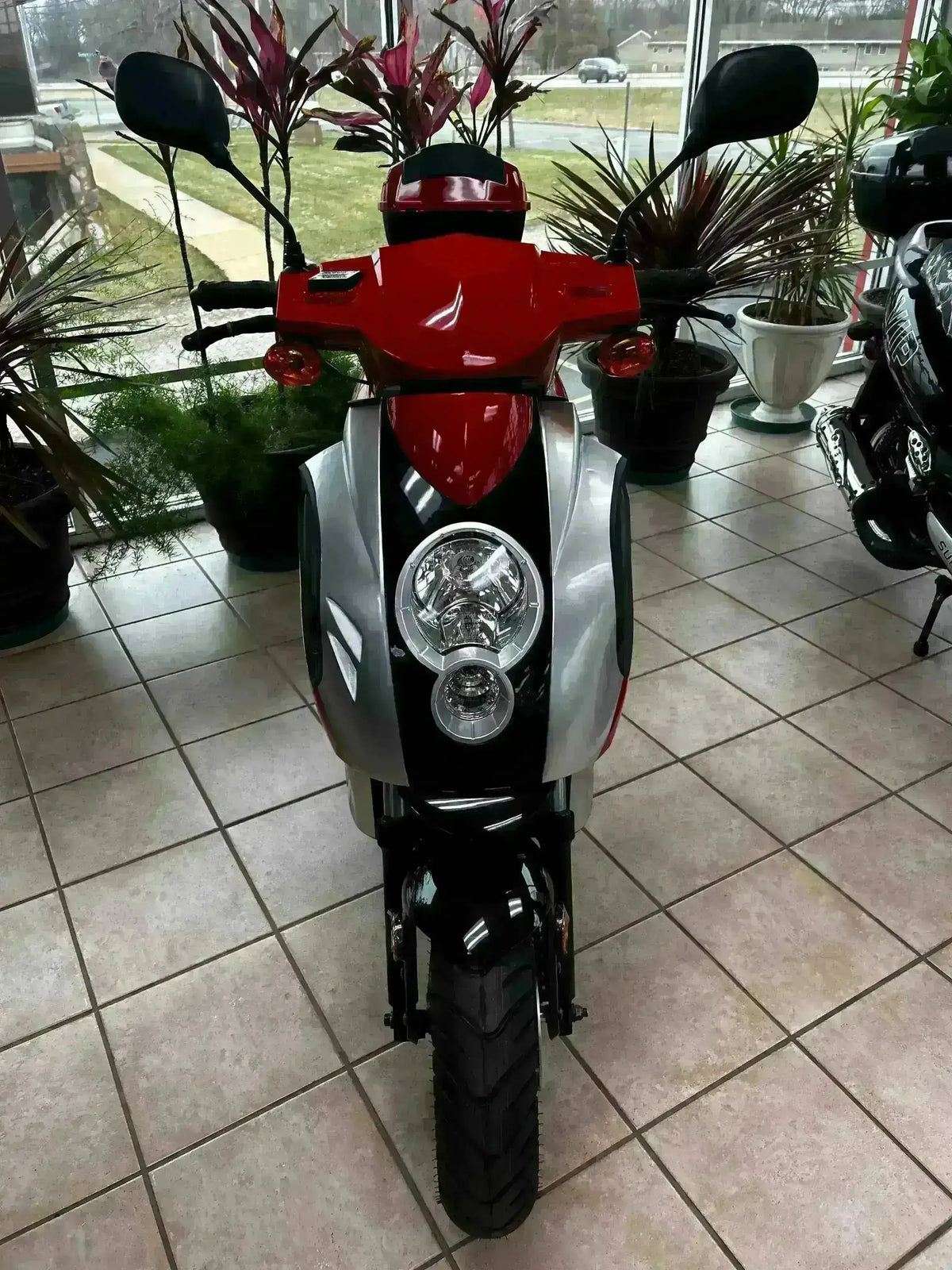 Red and silver 150cc scooter with dual headlights on showroom floor