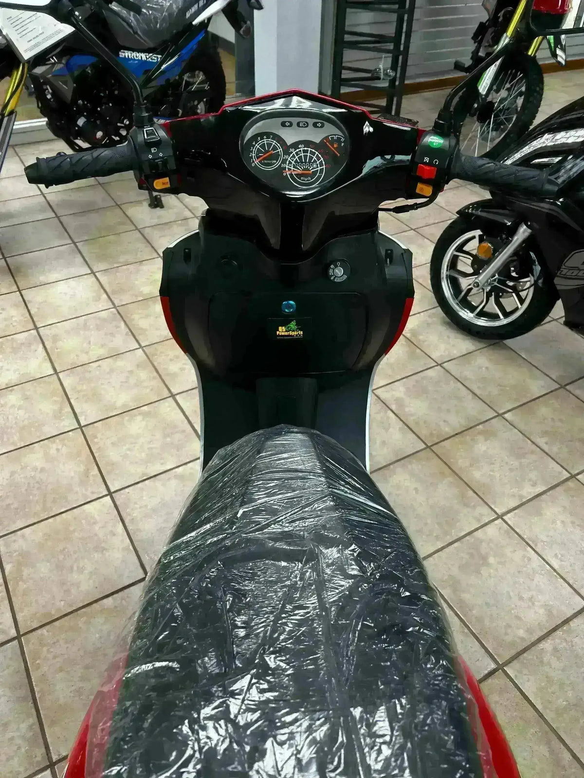 View from seat of a 150cc scooter with digital dashboard in a showroom setting