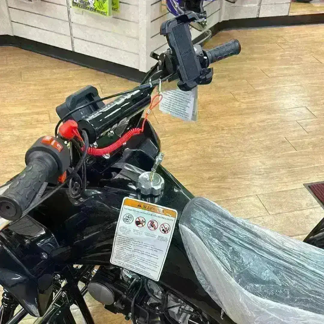 Handlebar-mounted cell phone holder on black ATV in showroom with safety tags visible.