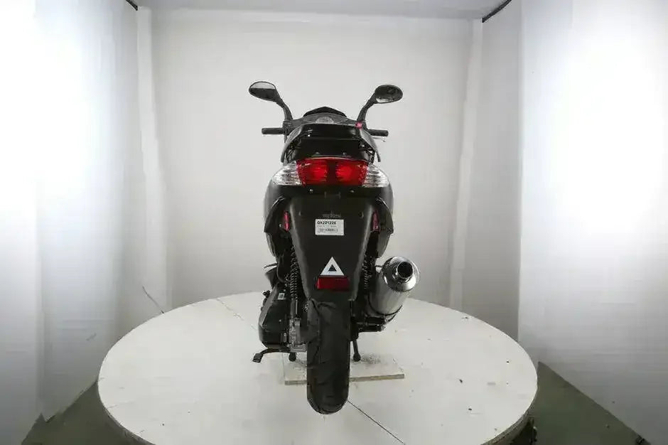 Rear view of the black RPS Adventure scooter showing taillight, rear tire and chrome exhaust on a display platform