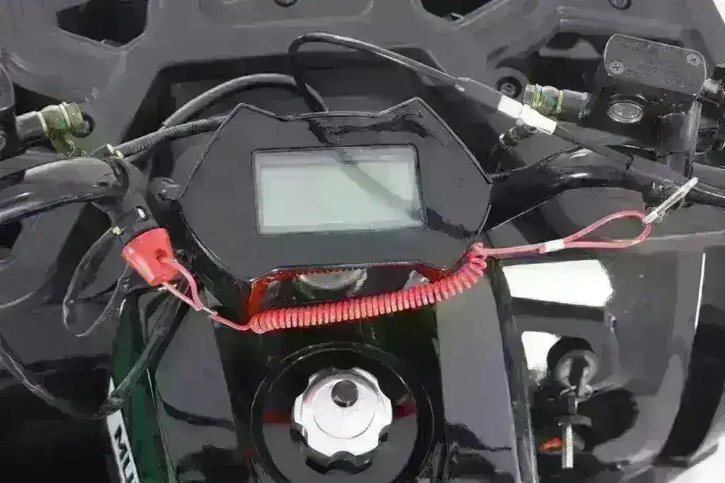 Close-up of ATV digital display, ignition key, and handlebar controls on a youth utility ATV.