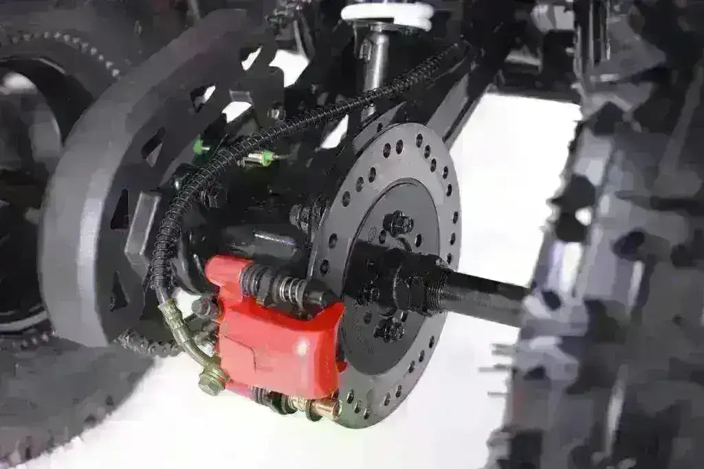 Close-up of youth ATV rear disc brake system with red caliper and off-road tire
