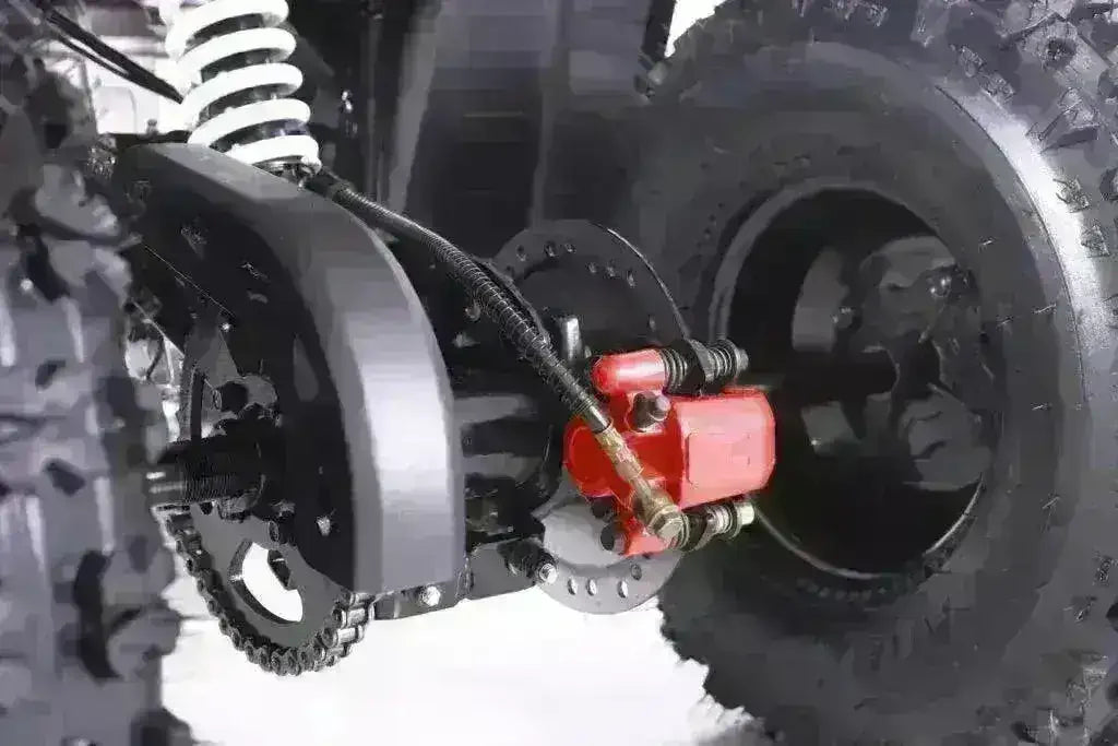 Close-up of youth ATV rear tire, suspension, and disc brake system on white background