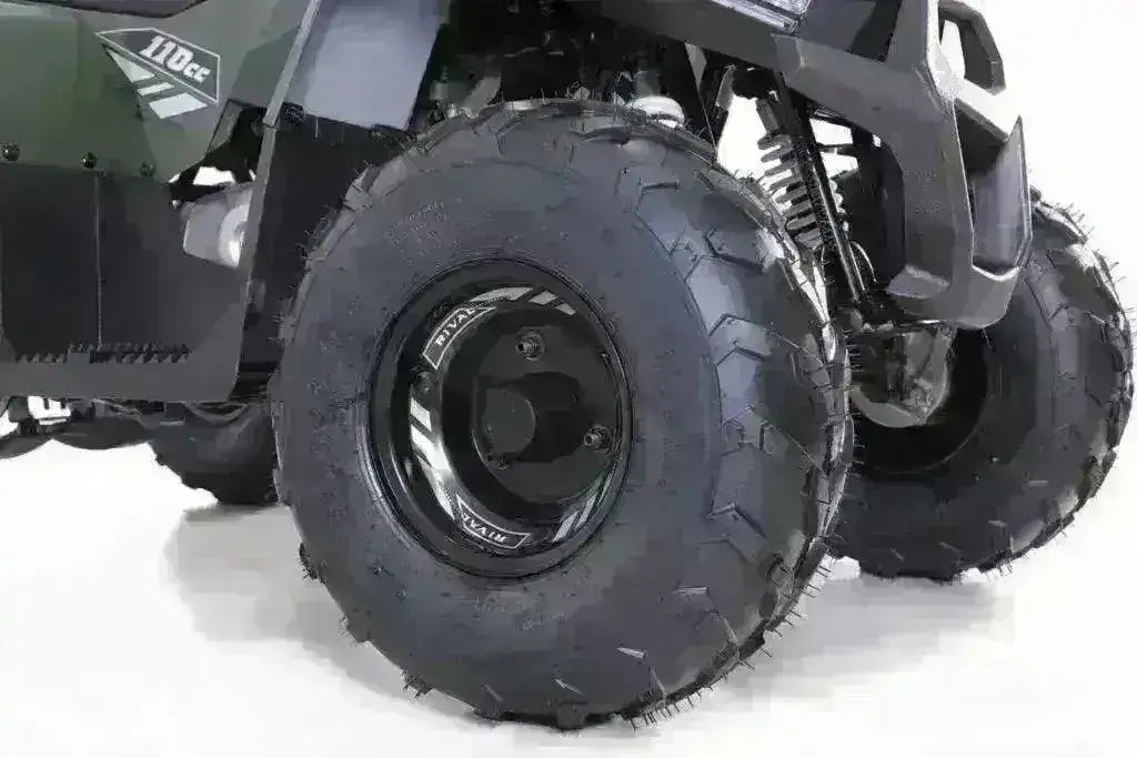Close-up of kids 110cc ATV rugged front tires and suspension on a white background