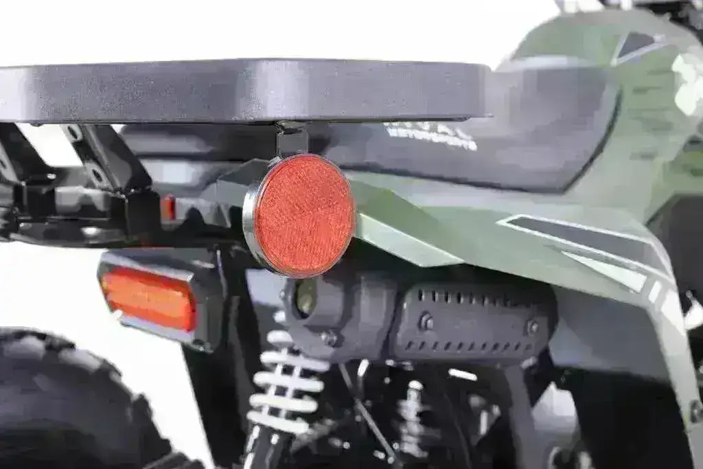 Close-up of the green Rival Mudhawk 6 ATV rear rack, round reflector, rectangular taillight and white suspension spring