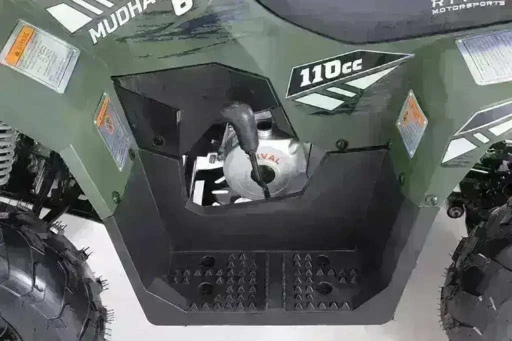 Close-up of the green Rival Mudhawk 6 ATV footwell, engine and shift lever beneath 110cc body graphics