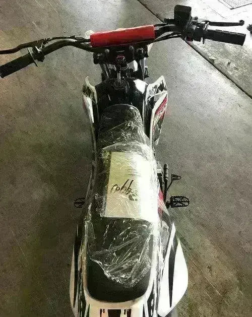 Youth dirt bike with black seat and handlebars, wrapped in plastic, at Q9 PowerSports USA.
