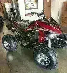 Red 200cc automatic sport ATV with large tires parked indoors on a concrete floor