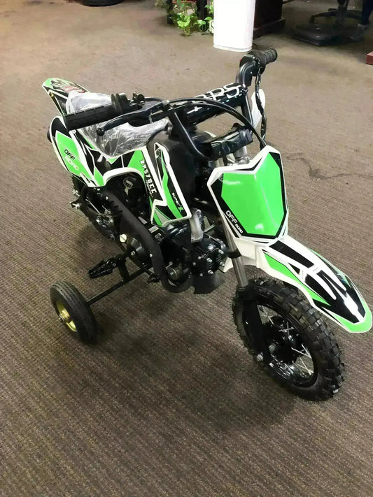 Green 70cc kids dirt bike with training wheels, off-road tires, on indoor carpet