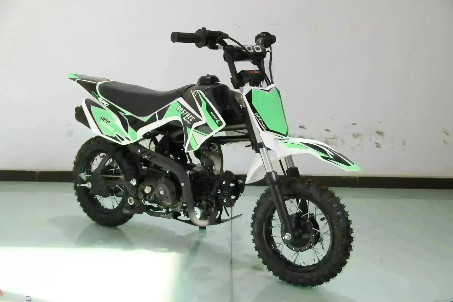 Green and black 70cc kids dirt bike with knobby tires and training wheels, indoors