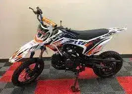 125cc dirt bike with off-road tires and colorful graphics on display indoors