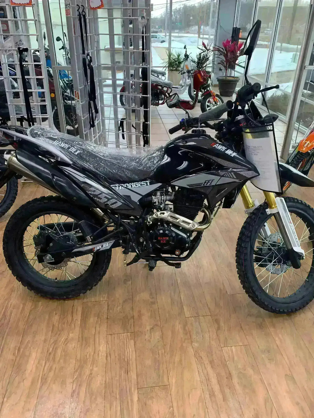 Black Hawk DLX 250 dual sport motorcycle on showroom floor with off-road tires