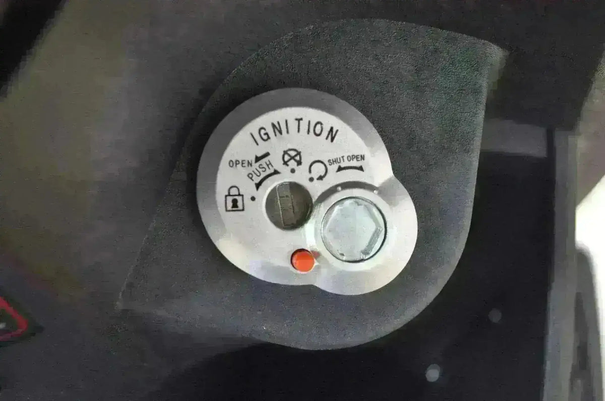 Close-up of a 50cc trike scooter ignition switch with lock and push start features.