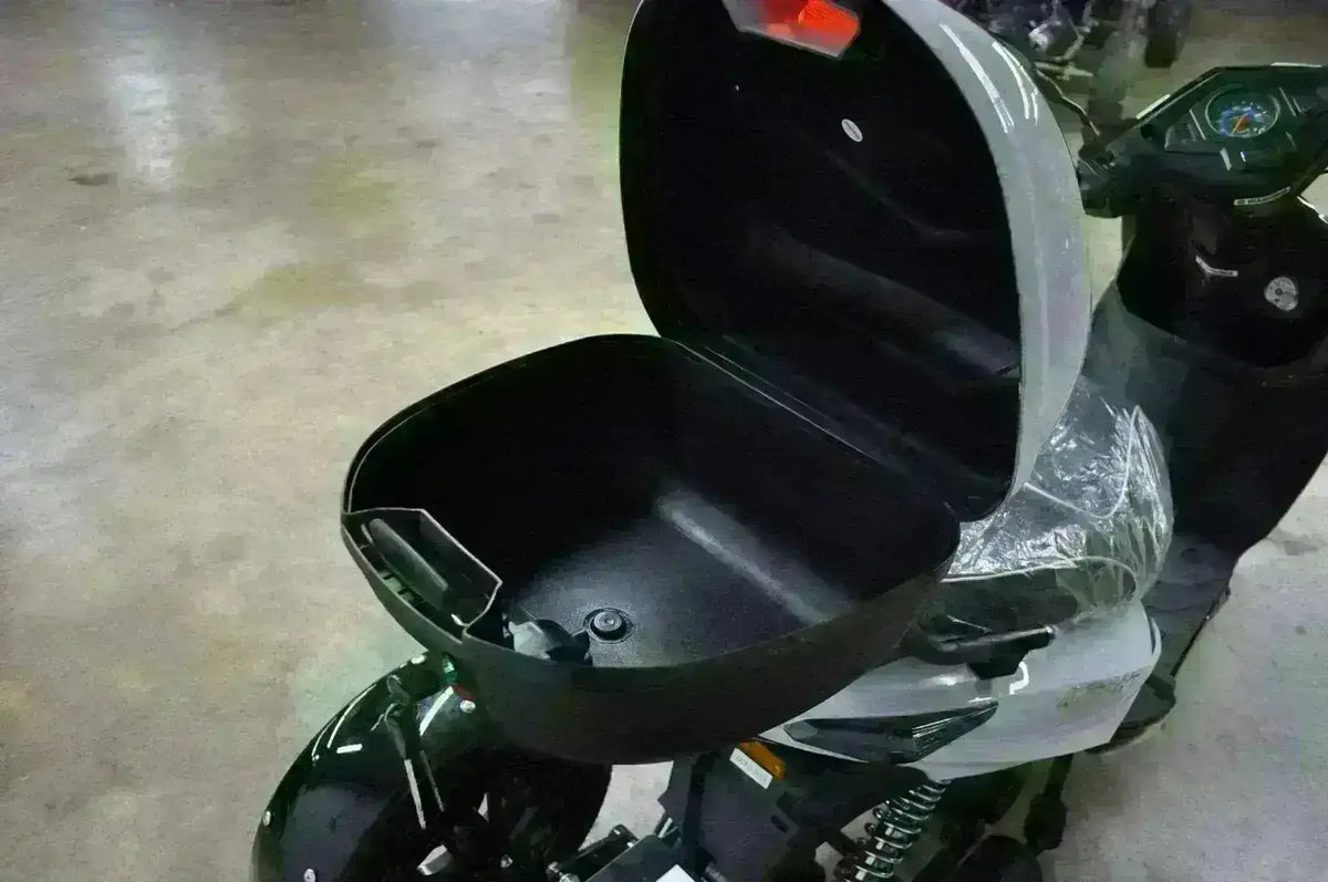 Open rear cargo storage compartment on a three-wheeled 50cc trike scooter indoors.