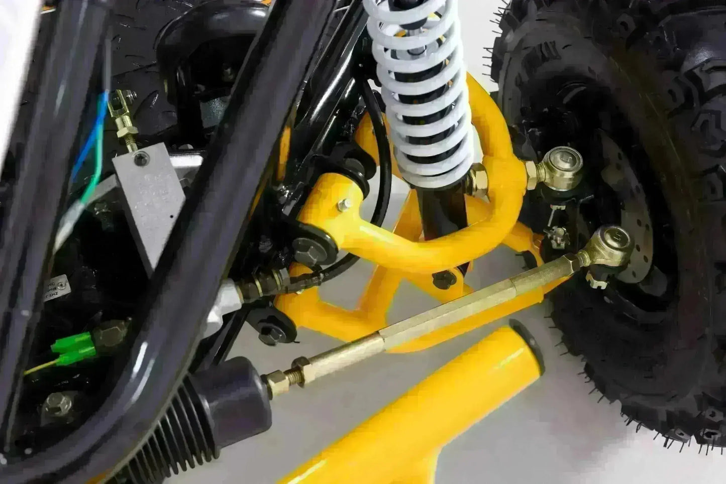 Close-up of the Triton go-kart yellow front control arms, white suspension spring and steering linkage
