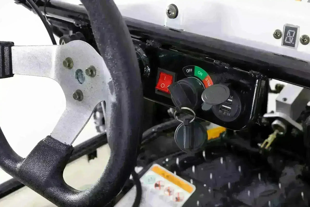 Close-up of the Triton go-kart ignition key, red rocker switch and covered charging socket beside the steering wheel