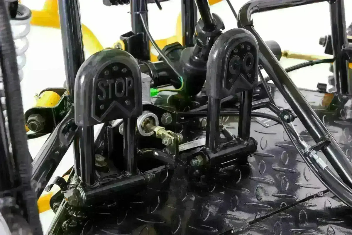 Close-up of brake and gas pedals labeled stop and go on a youth go-kart floorboard.