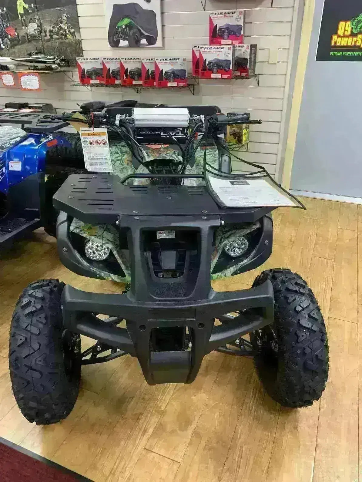 Front view of a youth ATV on display at Q9 PowerSports USA showroom with rugged tires.