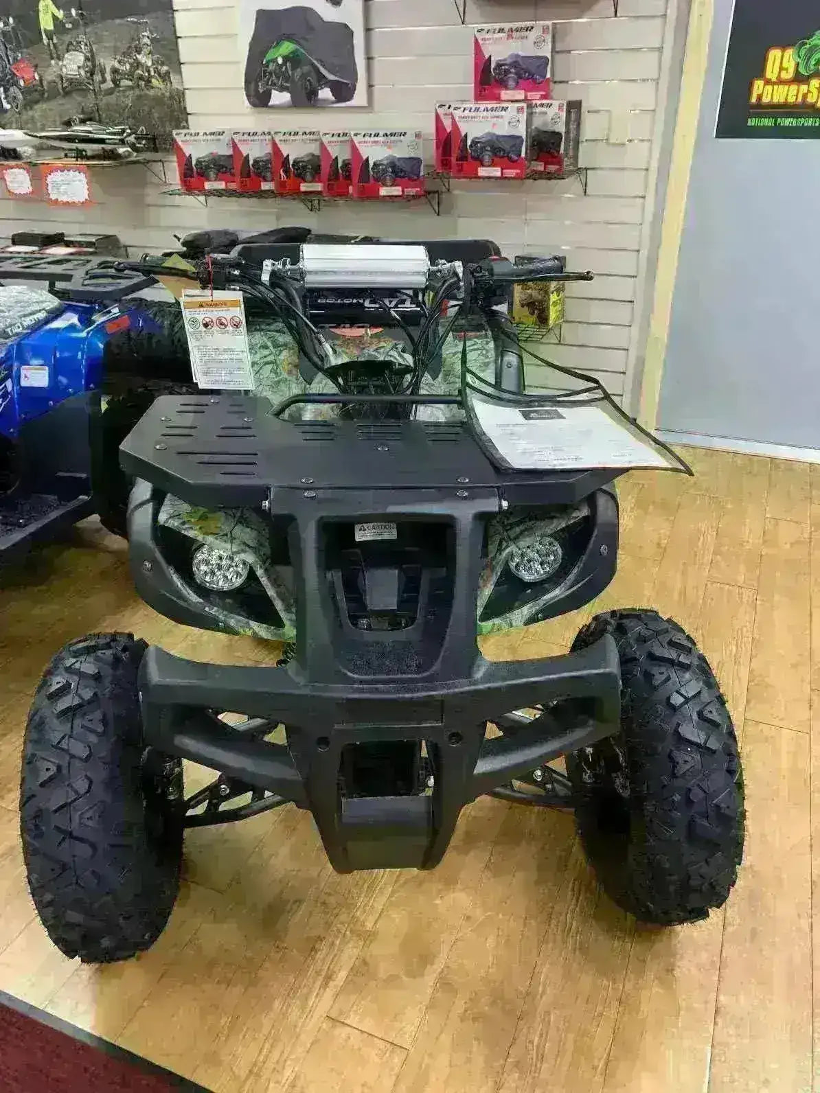 Front view of an off-road ATV with rugged tires and headlights in a showroom