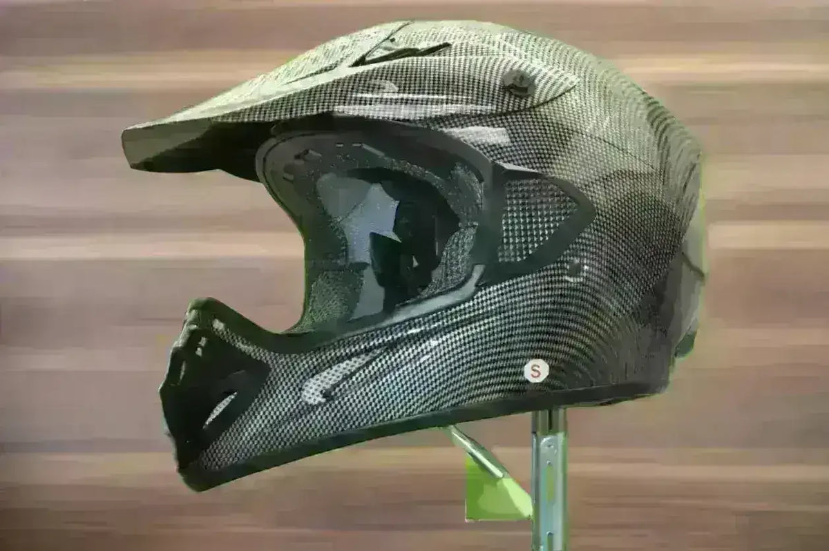 Black and gray carbon-pattern motocross helmet with peak visor and extended chin guard on display