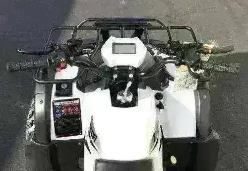 Top view of white 200cc utility ATV handlebars and dashboard on outdoor pavement
