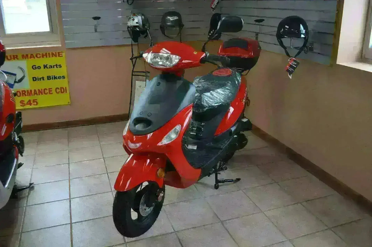 Red 50cc scooter on showroom floor with helmets displayed on wall in background
