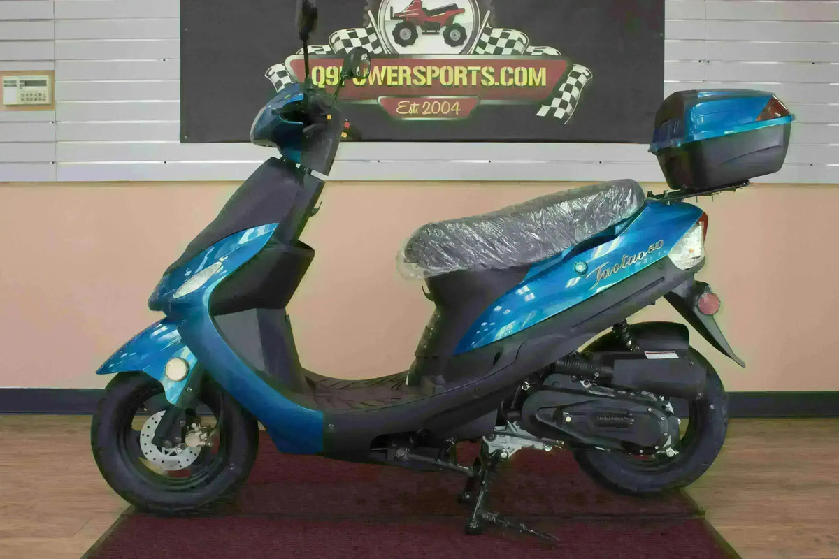 Blue 50cc scooter with rear storage box, side view, displayed indoors on showroom floor